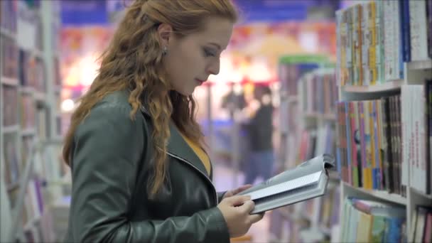 Porträtt av en ung vacker kvinna med ljust rött hår i glasögon, söt flicka läsning i bokbiblioteket University. — Stockvideo