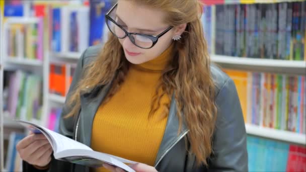 Portret Close Up of Happy Pretty Young Woman, Dziewczyna w okularach Student Czytanie w bibliotece książki University Standing w bibliotece Uniwersytetu w mieście. — Wideo stockowe