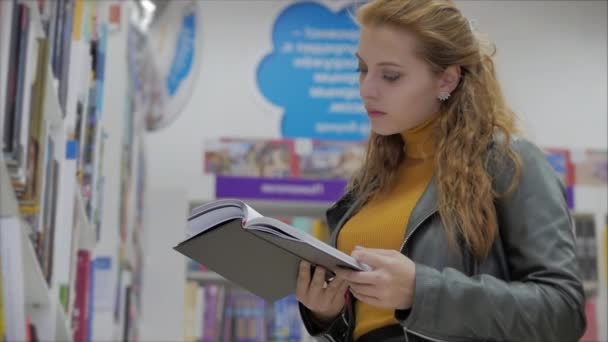 Портрет молодой красивой женщины с яркими рыжими волосами в очках, красивая девушка, читающая в библиотеке университета . — стоковое видео