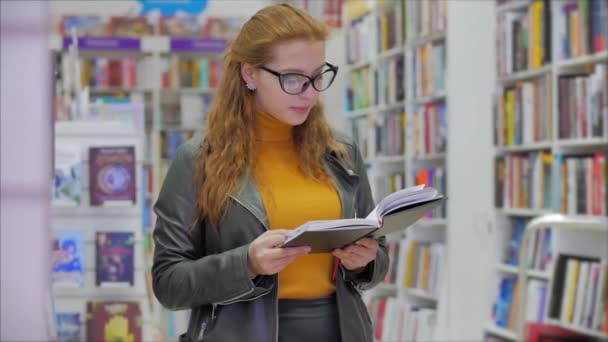 Porträt einer glücklichen hübschen jungen Frau, Mädchen mit Brille, Studentin, die in der Universitätsbibliothek liest und in der Universitätsbibliothek in der Stadt steht. — Stockvideo