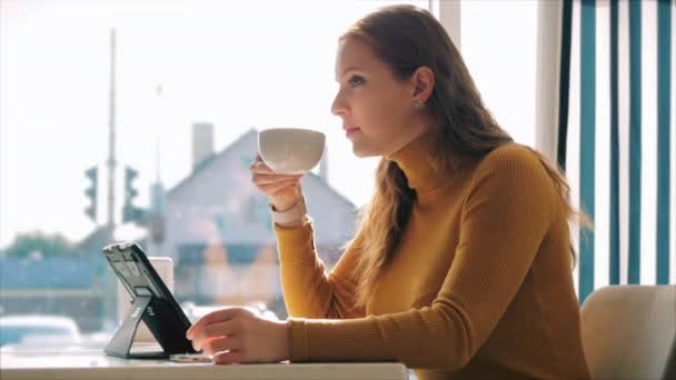 Portret close-up van gelukkig mooi jong vrouw, meisje zitten in een cafe werken aan een laptop, drinken ochtend koffie in de stad. — Stockvideo