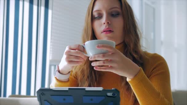 Retrato de cerca de la joven y bonita mujer feliz, niña sentada en un café trabajando en una computadora portátil, bebiendo café de la mañana en la ciudad . — Vídeos de Stock