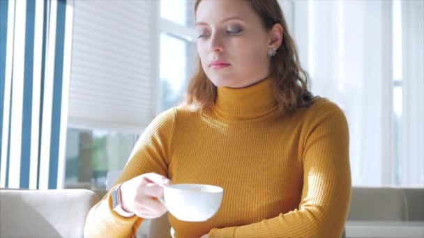 Retrato de cerca de la joven bonita y feliz, Chica sentada en un café, Beber café de la mañana en la ciudad . — Vídeo de stock