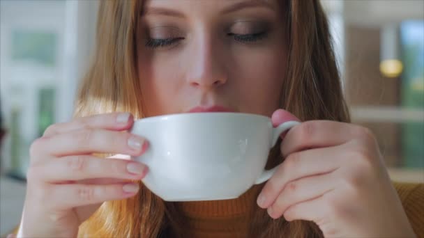 Retrato de cerca de la joven bonita y feliz, Chica sentada en un café, Beber café de la mañana en la ciudad . — Vídeo de stock