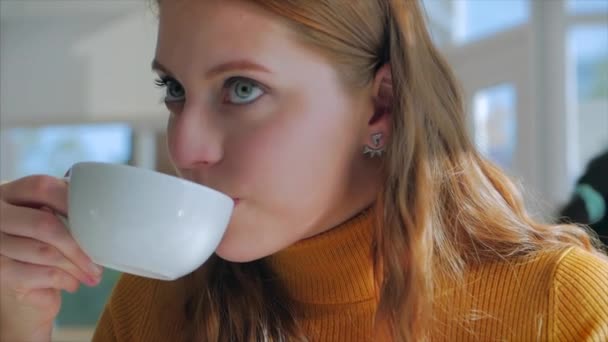 Retrato de cerca de la joven bonita feliz, Chica sentada en un café trabajando en una tableta, bebiendo café de la mañana en la ciudad — Vídeos de Stock