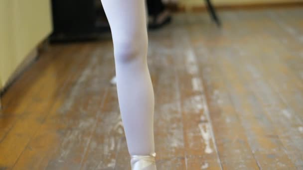 Gros plan d'une fille jambes en chaussures de ballet blanc sur un vieux plancher de bois pendant l'entraînement de ballet. Élément de l'exercice de danse classique . — Video