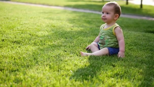 Aranyos kisbaba lassan mászik a réten vagy a zöld fűben. Egy kis gyerekvilág. Lassú mozgás. 4k.