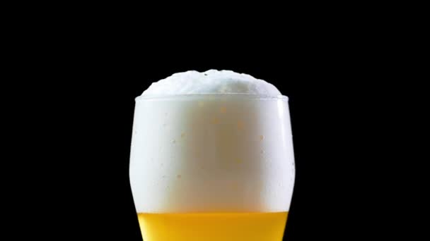 Bulles et mousse se déplacent dans le verre de bière. De la mousse glissant dans le verre de bière. Remplissage de bière dans le verre . — Video