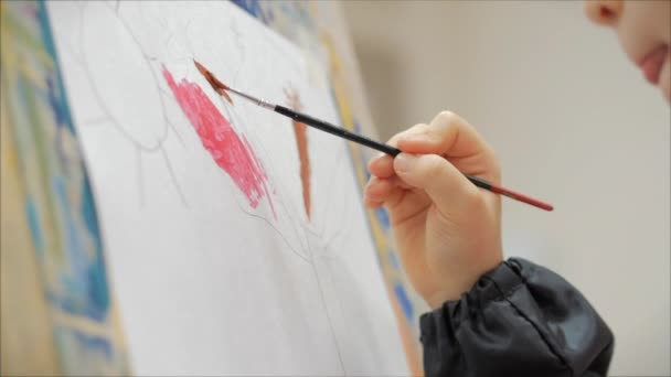 Junge Hände des Künstlers, kleine Mädchen Künstler bemalt eine Leinwand mit Pinsel, sitzt einen Tisch und zeichnen auf Leinwand. Prozess des Zeichnens: im Künstleratelier Hand Baby Girl Skizzen auf Leinwand. — Stockvideo