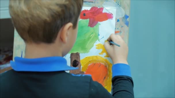 Young Hands of the Artist, Little Boy Artist Dipinge una Tela con Pennello, Seduto un Tavolo e Disegna su Tela. Processo di disegno: in Artisti Art Studio Hand Baby Girl Disegno su tela . — Video Stock