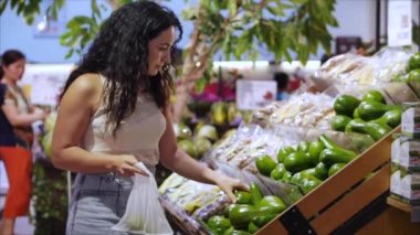 Güzel genç kadın ya da anne süpermarketten alışveriş yapıyor, süpermarketten yemek, sağlıklı yiyecekler, domates, avokado, meyve, portakal ve süpermarket ürünleri seçiyor..