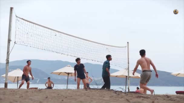 अलगाव संगरोध के बाद। कोविड-19। दोस्त सूर्यास्त में समुद्र तट वॉलीबॉल खेल रहे हैं, वॉलीबॉल स्पाइक सिनेमाई न्हा ट्रांग, वियतनाम में, 14 मई 2020 . — स्टॉक वीडियो