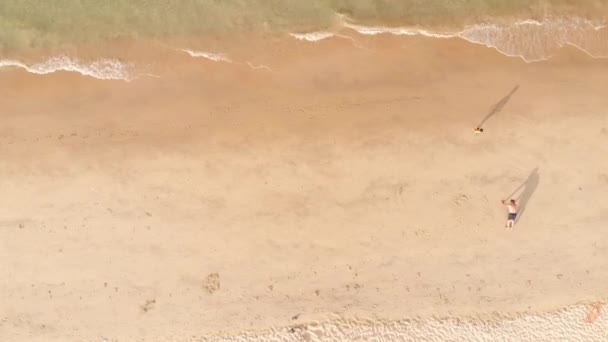 Letecký pohled na pláž shora, jen málo lidí, muž dělá kliky v písku, pláž po karanténě, po pandemii Kovid-19, asijské pláže. — Stock video