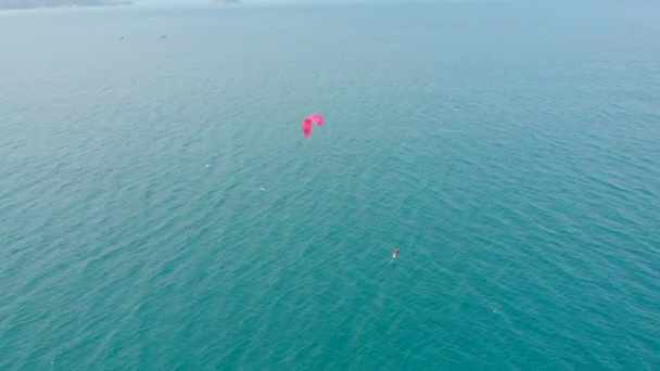 Luchtfoto van het stadsstrand en actieve mensen die kitesurfen en windsurfen beoefenen. Kitesurfen plaats, sport concept, gezonde levensstijl, menselijke vlucht. — Stockvideo