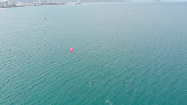 Vista aérea de la playa de la ciudad y gente activa practicando kitesurf y windsurf. Kitesurf lugar, concepto deportivo, estilo de vida saludable, vuelo humano. — Vídeos de Stock