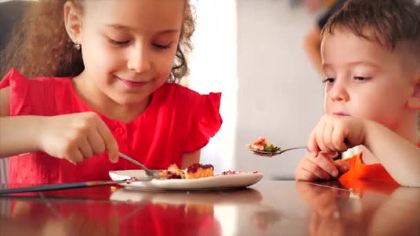 Niños muy felices comiendo tarta de queso. Hermana y hermano comen destilación que es pastel de pudín más rápido . — Vídeos de Stock