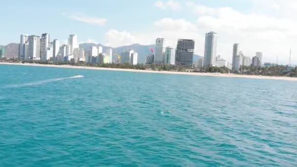 Vista aérea de la playa de la ciudad y gente activa practicando kitesurf y windsurf. Kitesurf lugar, concepto deportivo, estilo de vida saludable, vuelo humano. — Vídeos de Stock