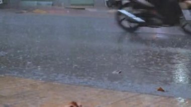 Büyük yaz ya da sonbahar yağmurları şehrin asfaltına düşer ve büyük bir su birikintisine dönüşerek caddeyi sular altında bırakır. Şiddetli yağmurda arabaları ve motosikletleri geçmek.