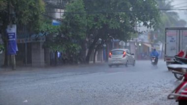 Şiddetli yağmurda arabaları ve motosikletleri geçmek. 29 Haziran 2020 'de şehrin asfaltına düşen yaz veya sonbahar yağmurları büyük su birikintilerine, sel baskınlarına dönüşür. Nha Trang, Vietnam, 29 Haziran 2020.