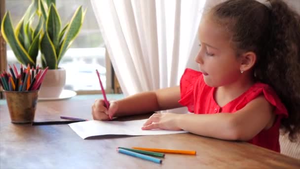 Carino piccolo artista bambina che gioca da solo disegno disegno disegno da colorare con a casa relax si siede in casa e dipinge su carta matite di colore uso. — Video Stock