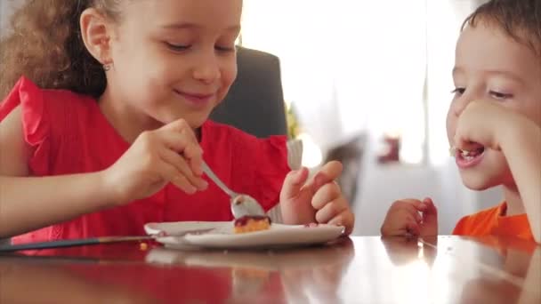 幸せな子供たちはチーズケーキを食べています。より速いプリンケーキである姉妹と弟は蒸留を食べる. — ストック動画