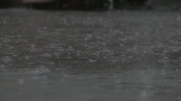 Gotas de perto de chuva de verão ou outono de água caem sobre asfalto na cidade transformando-se em uma grande poça, inundando a rua. As inundações são a estação chuvosa e chuvas fortes. Gotas de chuva caem . — Vídeo de Stock