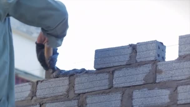 Gros plan sur les mains des maçons, travailleur volontaire masculin pose la brique dans le mur avec du ciment à l'aide de truelle, constructeur homme met les briques, à l'aide d'une ficelle tendue pour un niveau pair de matériaux de maçonnerie. — Video