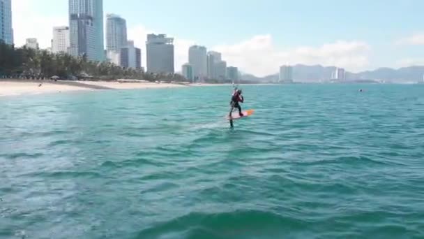 Luchtfoto van het stadsstrand en actieve mensen die kitesurfen en windsurfen beoefenen. Kitesurfen plaats, sport concept, gezonde levensstijl, menselijke vlucht. — Stockvideo