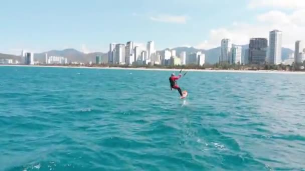 Kitesurfen plaats, sport concept, gezonde levensstijl, menselijke vlucht. Luchtfoto van het stadsstrand en actieve mensen die kitesurfen en windsurfen beoefenen. — Stockvideo