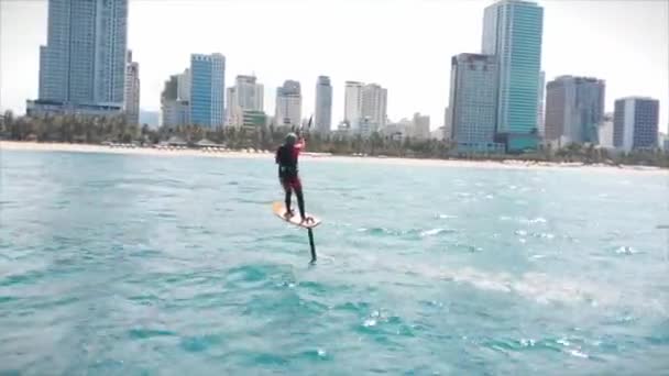 Vista aerea sulla spiaggia della città e persone attive che praticano kite surf e windsurf. Luogo di kitesurf, concetto di sport, stile di vita sano, volo umano. — Video Stock