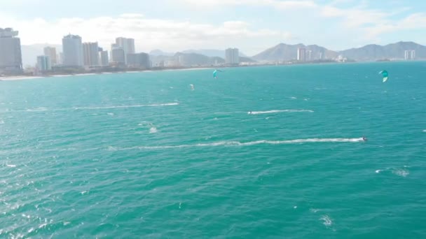 Kite surfing místo, sportovní koncept, zdravý životní styl, lidský let. Letecký pohled na městskou pláž a aktivní lidi praktikující kite surfing a windsurfing. — Stock video