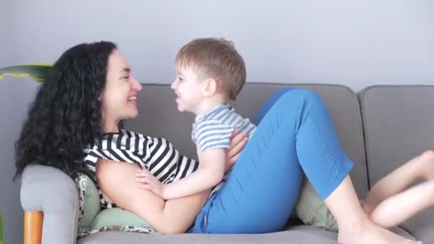 Boldog egészséges család fiatal anya emelés aranyos kis gyermek fia fel játszani sík kanapén otthon, vicces gyerek repülő anyák gyakorolni sport. — Stock videók