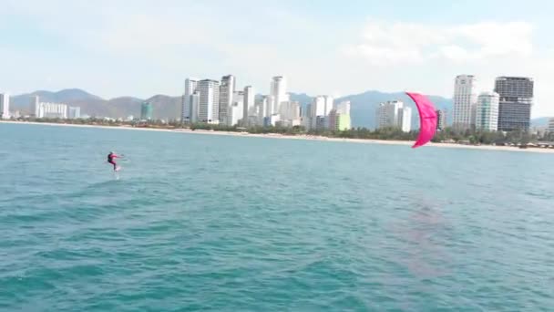 Vlieger surfplaats, sportconcept, gezonde levensstijl, menselijke vlucht. Luchtfoto van het stadsstrand en actieve mensen die kitesurfen en windsurfen beoefenen. — Stockvideo
