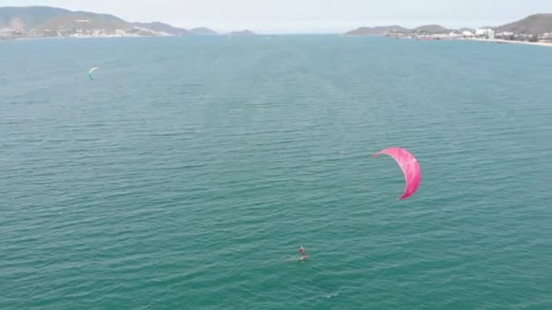 Kite surf lugar, conceito de esportes, estilo de vida saudável, voo humano. Vista aérea da praia da cidade e pessoas ativas praticando kite surf e windsurf. — Vídeo de Stock