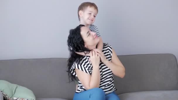 Lycklig familj koncept. Söt tillgiven son kramar mor till föräldrar med slutna ögon, bedårande barn, son eller dotter kramar mamma, kramar, njuter av ömma söta ögonblick. — Stockvideo