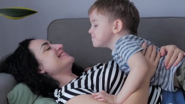 Lycklig familj koncept. Söt tillgiven son kramar mor till föräldrar med slutna ögon, bedårande barn, son eller dotter kramar mamma, kramar, njuter av ömma söta ögonblick. — Stockvideo