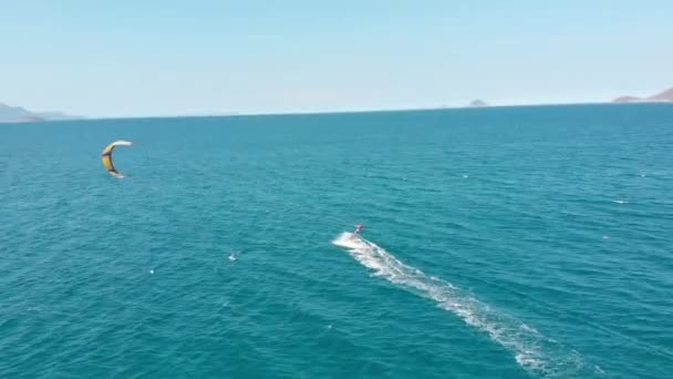 Salto acrobático de surfista cometa profesional en la ola del mar, atleta mostrando truco deportivo saltando con cometa y tabla en el aire. Deportes acuáticos extremos y concepto de vacaciones de verano — Vídeo de stock