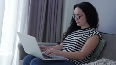 Evde dizüstü bilgisayarda yazan bir kadın, evdeki koltukta oturan bir iş kadını evde oturup akıllı telefon kontrolleri yapan bir iş kadını evde internetten öğrenim görmek için mektupları kontrol ediyor..