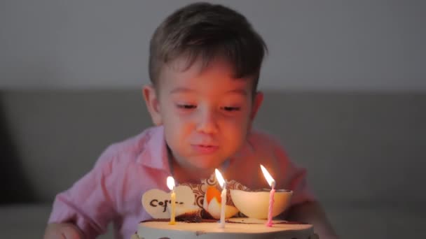 Концепція щасливої сім'ї. Щасливий маленький хлопчик два роки святкує свій день народження зі своєю сім'єю, мати і сестра допомогли йому підірвати свічки. . — стокове відео