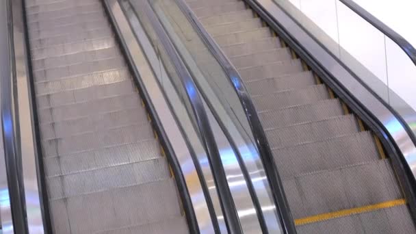 Remontez l'escalier roulant avec des côtés en verre et des marches en métal. Escalator déménagement dans le centre commercial. — Video