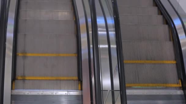 Προχωρώντας το Escalator με γυάλινες πλευρές και μεταλλικά σκαλοπάτια. Escalator κινείται στο εμπορικό κέντρο. Κλείσιμο προβολής. Άνθρωποι η μάσκα Covid-19. — Αρχείο Βίντεο