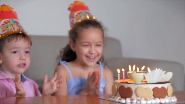 Happy Little Children Nettes Mädchen und sein kleiner Bruder betrachten die brennenden Kerzen auf Kuchen an ihrem Geburtstag, feiern Geburtstag mit der Familie und pusten Kerzen auf der Torte bei der Destillation aus. — Stockvideo