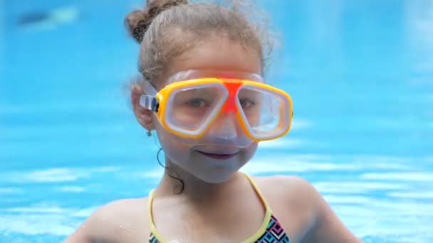 Πορτρέτο κοριτσάκι σε μια υποβρύχια μάσκα επιπλέουν σε μια εξωτερική πισίνα.Ενεργό υπόλοιπο στο υδάτινο πάρκο. Happy Kid ή το παιδί προετοιμασία για diving.Girl σε αναπνευστήρα αύξηση αντίχειρα κάνει ok σημάδι πριν από την κατάδυση. — Αρχείο Βίντεο
