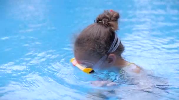Porträtt av en liten flicka i en undervattensmask som flyter i en utomhuspool. Aktiv vila i vattenparken. Glad barn.Barnet förbereder sig för dykning i havet — Stockvideo