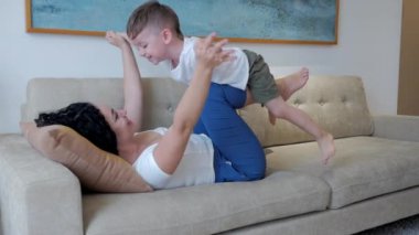 Çocuk oyun oynuyor. Annesi kim? Mutlu sağlıklı bir aile, genç bir anne, küçük tatlı bir çocuğu kaldırıyor. Evdeki kanepede uçuyor. Komik çocuk, annesinin antrenmanında..