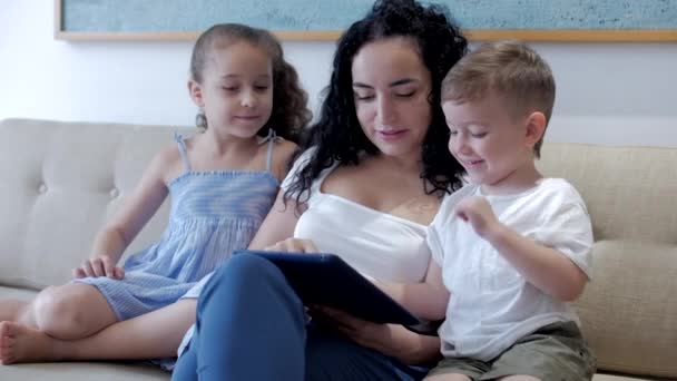 Família feliz, mamãe e crianças pequenas bonitos assistir o telefone, mamãe brinca com as crianças em casa, relaxando usando um smartphone, abraçando, sentado no sofá, rindo, se divertindo, desfrutando de momentos de — Vídeo de Stock