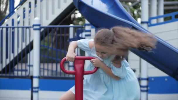 Glücklich lächelndes Mädchen im Freien, spielendes Kind auf einer Schaukel im Park. Babygefühle. Sommersonniger Tag Kleine Kinder oder glückliche Kinder spielen im Freien. Kinderaktivitäten. — Stockvideo