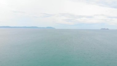 Denizin arka planında ve küçük balıkçı mercanlarında bir dağın insansız hava aracı görüntüsü. Vahşi yaşam manzarası, dramatik gökyüzü, bulutlar yüzüyor.