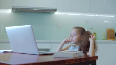 Küçük kız, 7-8 yaşlarında, evde eğitim gören sevimli bir ilkokul çocuğu, evde ders dinliyor, ev ödevlerini evden çıkmadan yapıyor. Çocuk eğitimi, çocuk eğitimi konsepti.