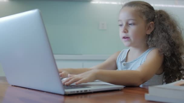 Μικρό κορίτσι ένα χαριτωμένο παιδί του δημοτικού σχολείου 7-8 ετών στο σπίτι σπουδάζει στην οικογενειακή μάθηση ακούει διαλέξεις σχολείο κάνει την εργασία χωρίς να αφήνει το σπίτι. — Αρχείο Βίντεο